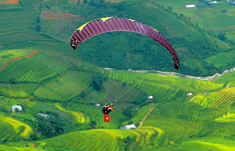 Paraglider flying over the rice terraces below Khau Pha Pass in Mu Cang Chai